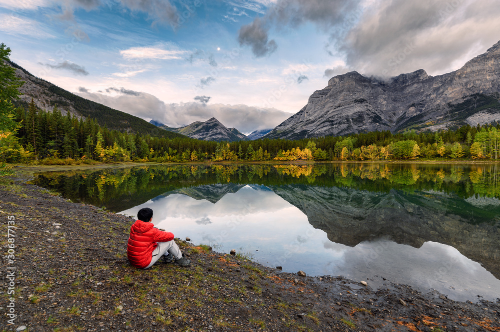 Man traveler relaxing in Wedge pond at morning on Kananaskis country Man traveler relaxing in Wedge pond at morning on Kananaskis country