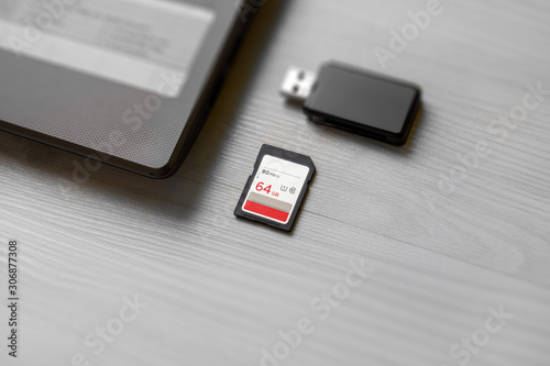 SD memory card on table beside laptop computer and card reader