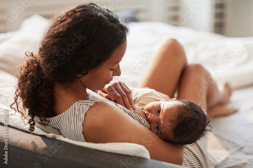 High angle portrait of young African-American mother breastfeeding cute baby boy with child looking at camera, copy space photo