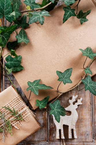 Christmas background with ivy leaves, deer and beautifully wrapped gift.