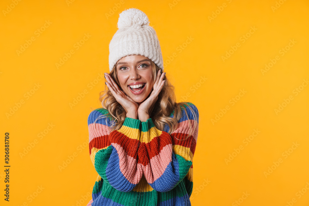 Image of happy blonde woman in winter hat and sweater smiling at camera Image of happy blonde woman in winter hat and sweater smiling at camera