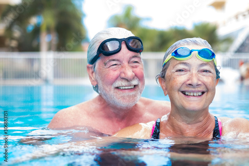 beautiful and cute close up of two seniors in the pool having fun together - fitness and healthy lifestyle - summertime together