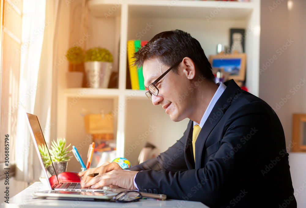 Casual businessman working in office, sitting at desk, typing on keyboard, looking at computer screen.