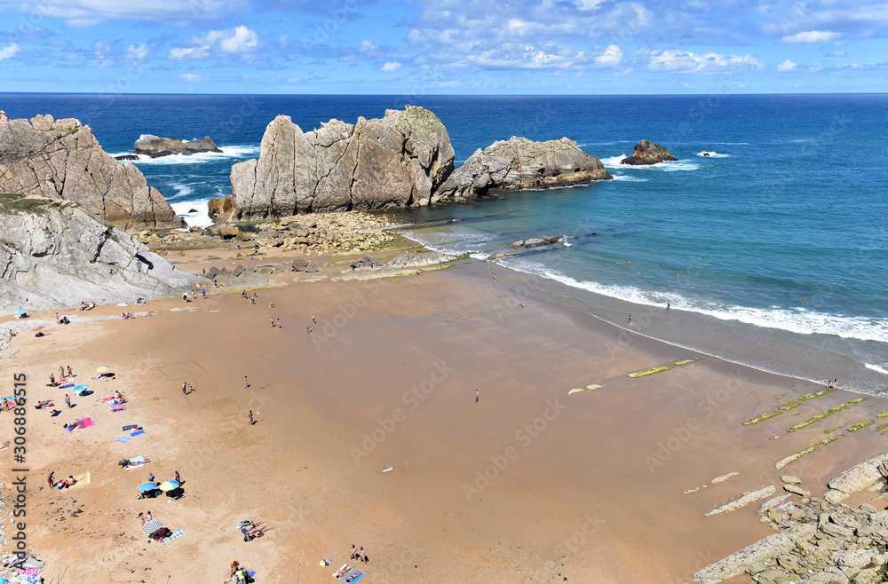 Tourists enjoying the sun in the beach of Playa De La Arnia on a sunny day, Santander. Cantabria, Spain