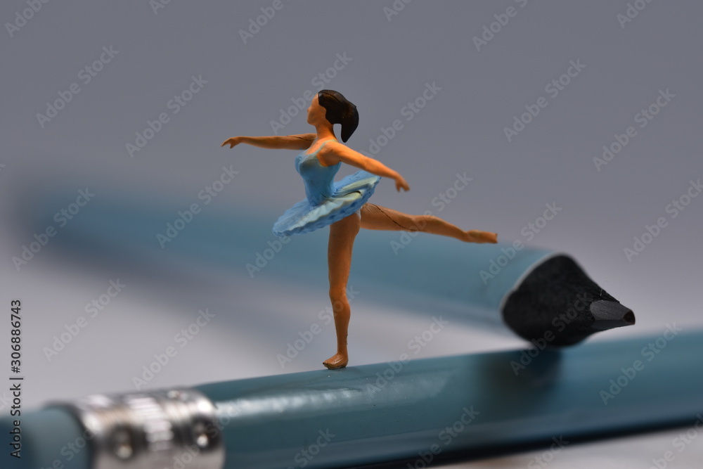 Tiny ballerina dancer in blue dress standing on one leg