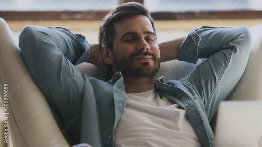 Calm happy healthy young man resting breathing on comfortable armchair
