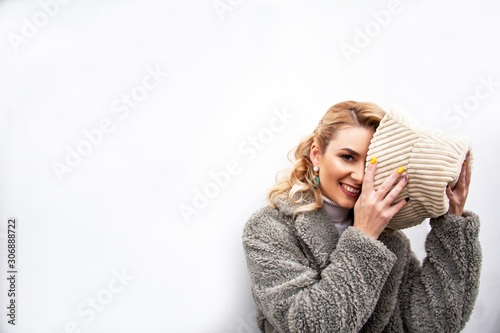 Fashion woman posing at the background street brick wall, dressed modern clothes. Female model wearing faux fur coat, tutleneck, skirt and bag