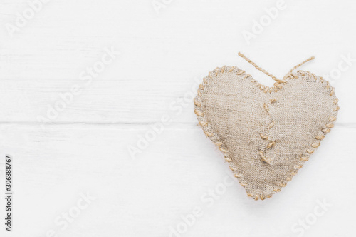 Darned heart on a wooden white background. Top view