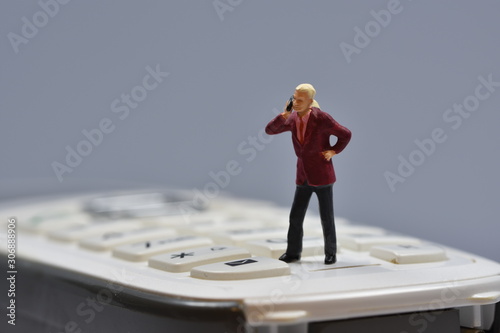 miniature man standing on a phone talking with a smartphone