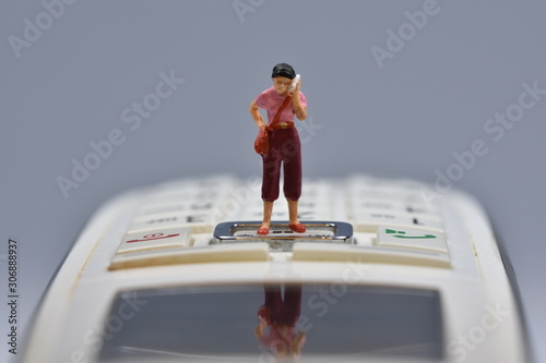 little woman is standing on a phone, talking on a cellular phone