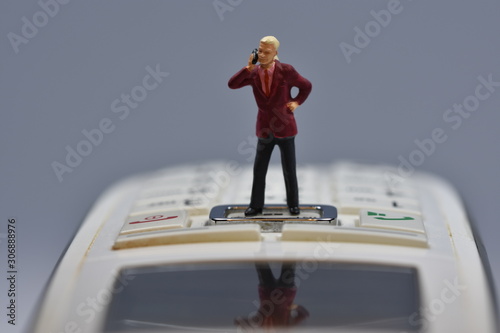 miniature man standing on a phone talking with a smartphone