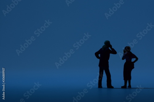 two tiny people talking on a smartphone