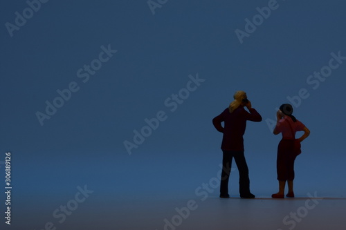 two tiny people talking on a smartphone