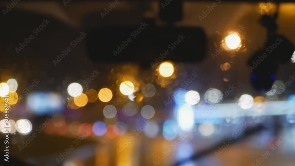 Rainy dark night view of the movement of the wipers from the passenger compartment. Night city through the car window Rainy dark night view of the movement of the wipers from the passenger compartment. Night city through the car window