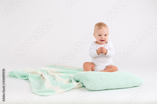 Kid boy sitting on the plush striped double colored blanket on the white background