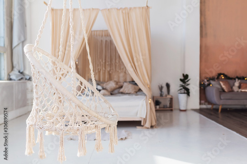 Cosy light bedroom with eco decor. Nature concept in interior of room. Scandinavian interior, real photo. Hygge decoration.Modern scandinavian bedroom with bed and plants. Rope swing in interior.