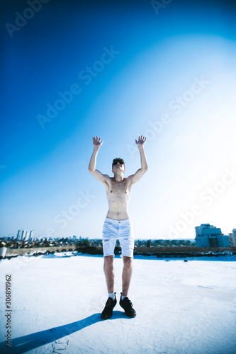 Young attractive man posing in front of camera on the roof of a residential building. Hands up in the air © Victoria Key
