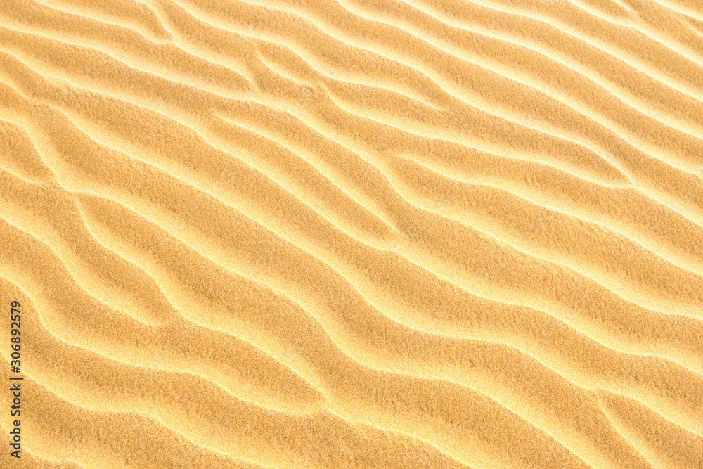 Pebble lying on texture of yellow sand dunes. Can be used as natural background Pebble lying on texture of yellow sand dunes. Can be used as natural background