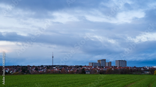 Germany, Skyline of stuttgart city with skyscrapers and famous landmark tv tower building behind green fields and houses on stormy day