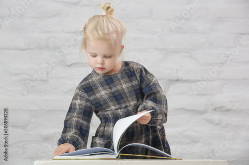 Portrait of adorable blonde toddler girl holding a book