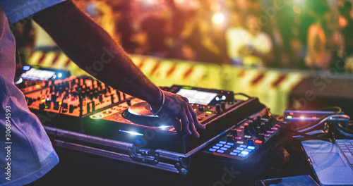 Dj mixing outdoor at new year party festival with crowd of people in background - Nightlife view of disco club outside - Soft focus on bracelet, hand - Fun ,youth,entertainment and fest concept photo