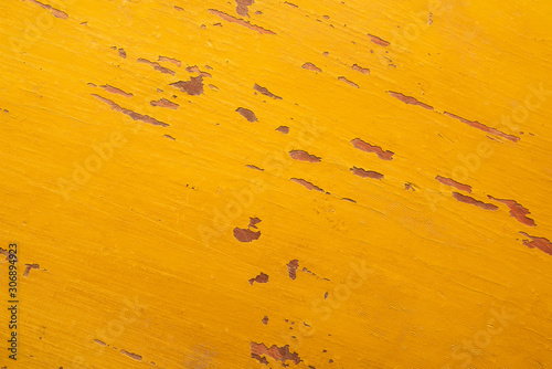 Texture of peeling yellow paint on an old wooden surface.