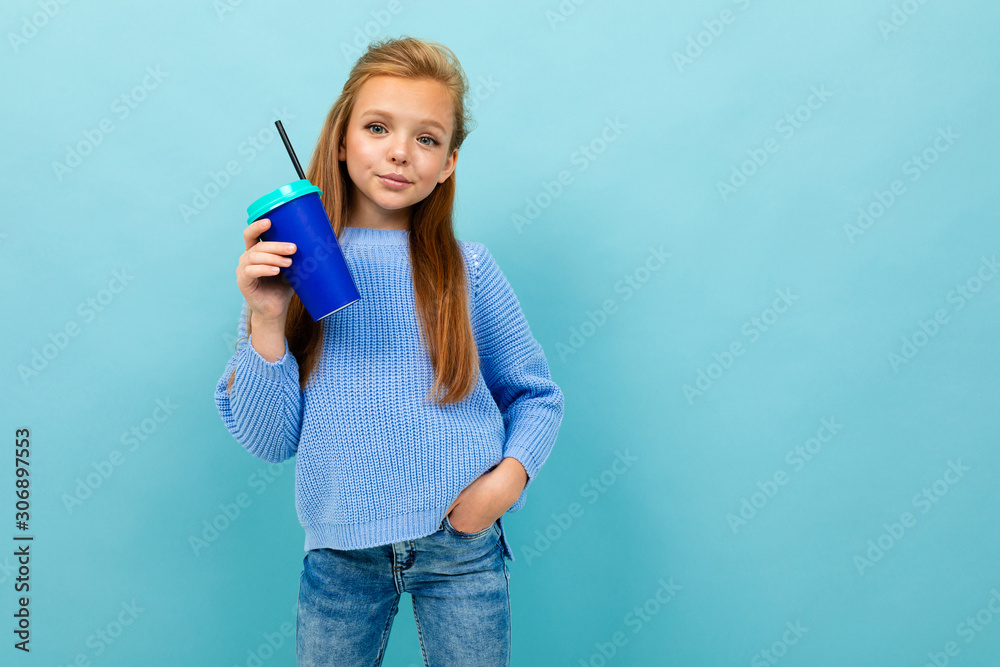 portrait of a european girl drinking holding a glass on a light blue wall portrait of a european girl drinking holding a glass on a light blue wall