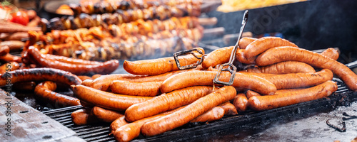 Roasted fat smoked and grilled pork legs, sausages, shashliks at christmas fair market. photo