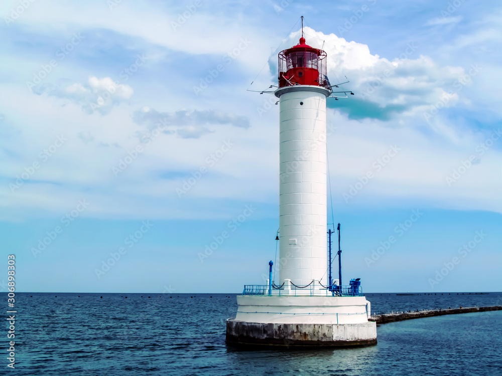 Vorontsov lighthouse in Odessa against the background of the Black Sea, close-up. White tower with a red cabin at the top on a background of blue seascape Vorontsov lighthouse in Odessa against the background of the Black Sea, close-up. White tower with a red cabin at the top on a background of blue seascape
