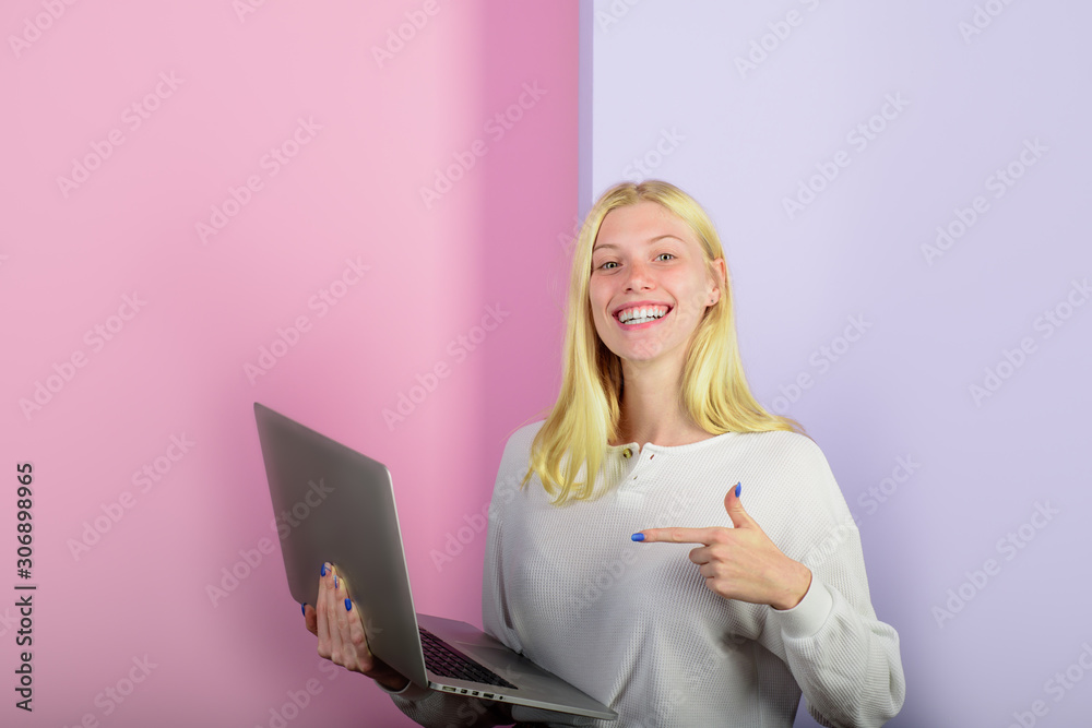 Smiling girl pointing finger on personal computer. Woman shows finger on laptop computer. Student girl with laptop. Work from home. Modern technology, internet, communication. Trendy girl with laptop. Smiling girl pointing finger on personal computer. Woman shows finger on laptop computer. Student girl with laptop. Work from home. Modern technology, internet, communication. Trendy girl with laptop.