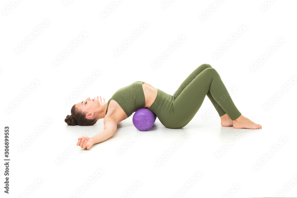 European brunette girl in a green sports suit goes in for sports with a simulator on a white background European brunette girl in a green sports suit goes in for sports with a simulator on a white background