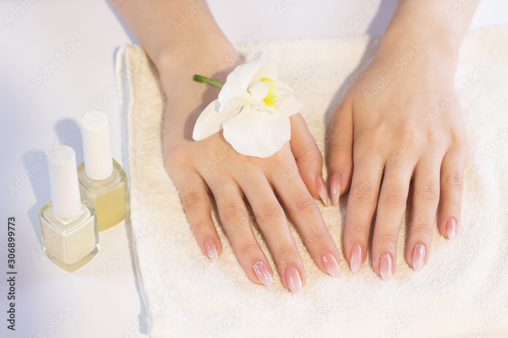Beautiful soft woman hands with light manicure hand care and spa relaxing white orchid nail polish towel copy space