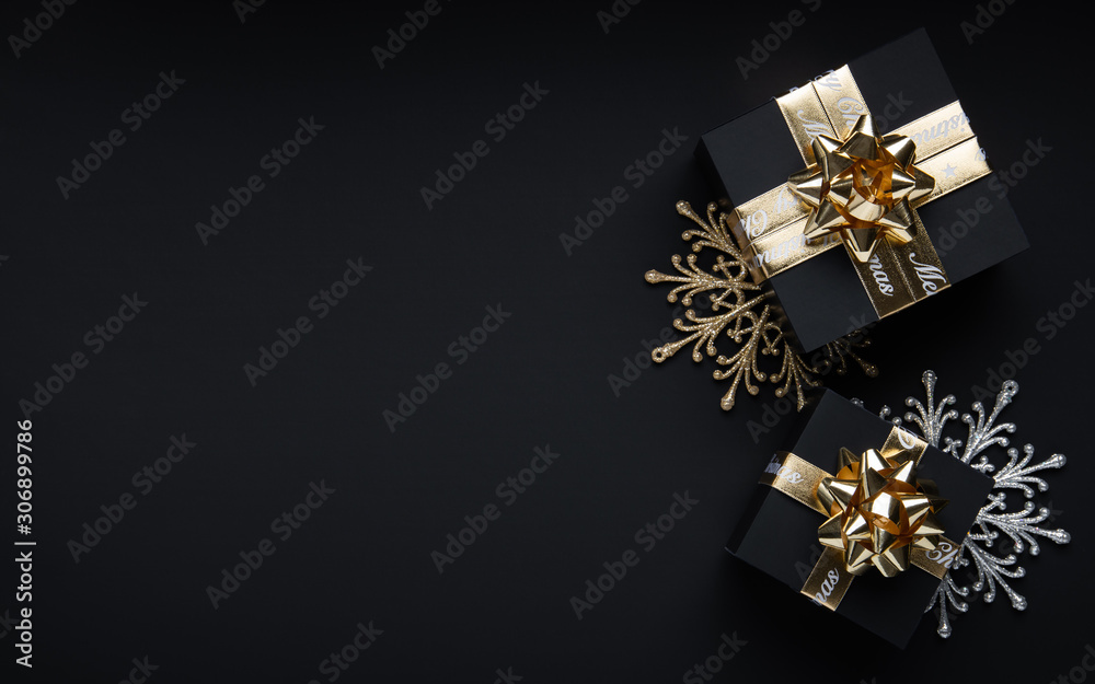 Merry Christmas and Happy Holidays greeting card, frame, banner. New Year. Noel. Christmas golden ornaments and gift on black background top view. Winter xmas holiday theme Merry Christmas and Happy Holidays greeting card, frame, banner. New Year. Noel. Christmas golden ornaments and gift on black background top view. Winter xmas holiday theme