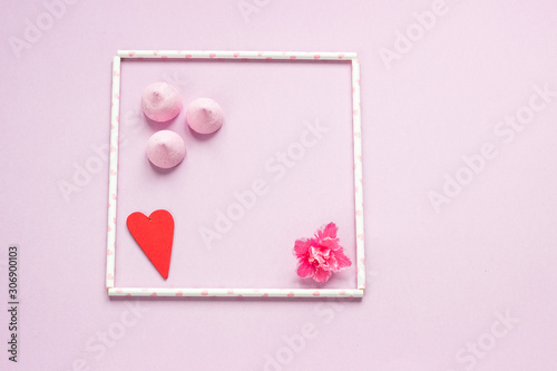 Frame from pink drinking ecofriendly straws with red heart, pink flower and small pink meringues. Valentine’s Day concept.