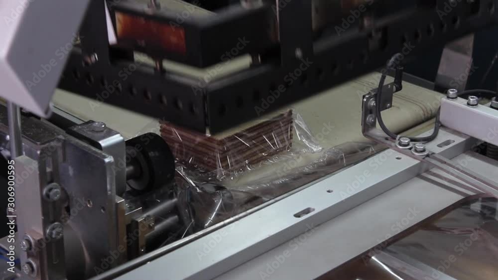 Delicious, chocolate wafers are packed in a transparent film on an automatic conveyor, without the participation of people. Delicious, chocolate wafers are packed in a transparent film on an automatic conveyor, without the participation of people.