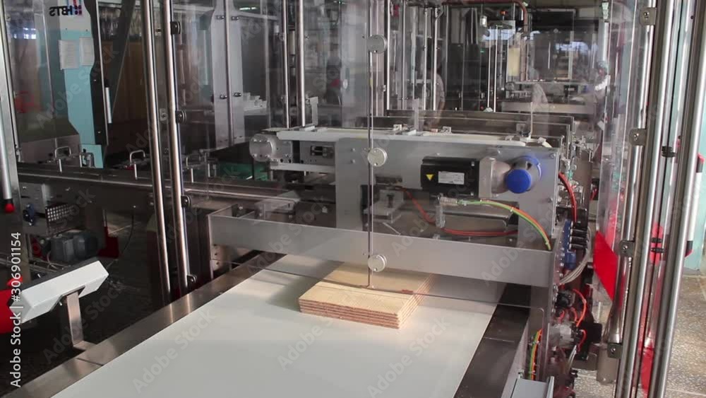 Folded, one on another, wafer tiles move along a conveyor belt. Folded, one on another, wafer tiles move along a conveyor belt.