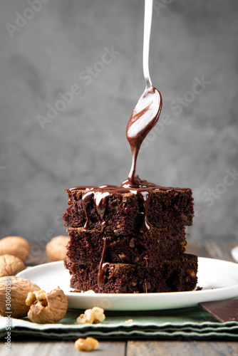 Pouring melted chocolate on brownies with a spoon