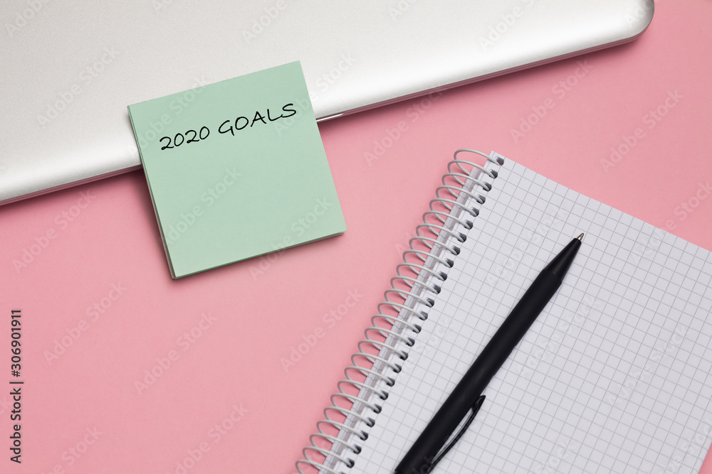2020 goals text on notepad with pen on pink background. Business motivation, inspiration concept.