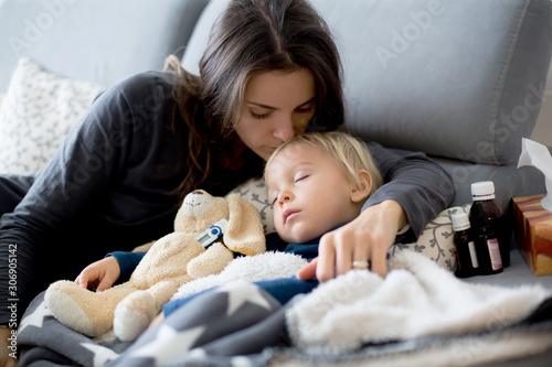 Canvas Print Blond toddler boy, sleeping on the couch in living room, lying down with fever