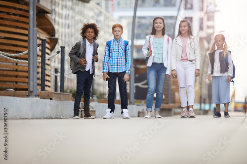 Group of multiethnic children walking together along the street in summer day
