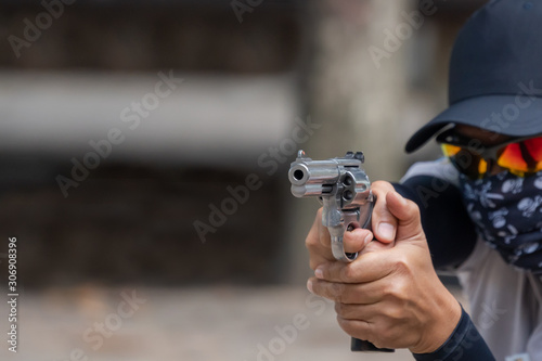 Man holding gun aiming pistol in hand ready to shoot. The criminal robber or gangster thief concept