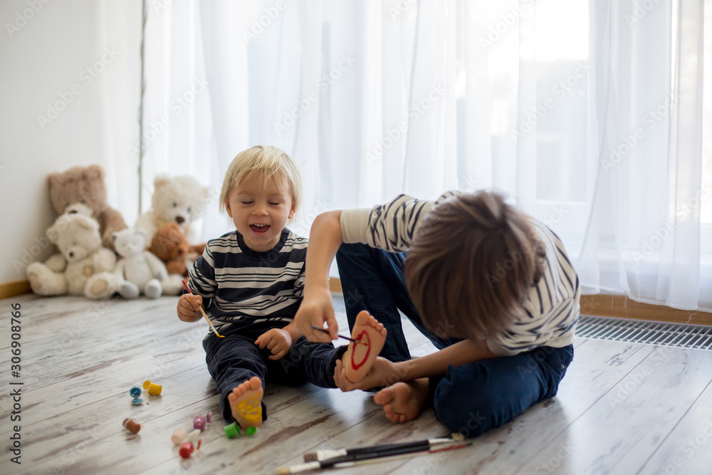 Obraz premium Brothers, playing at home, painting on their feet, tickling, laughing, smiling