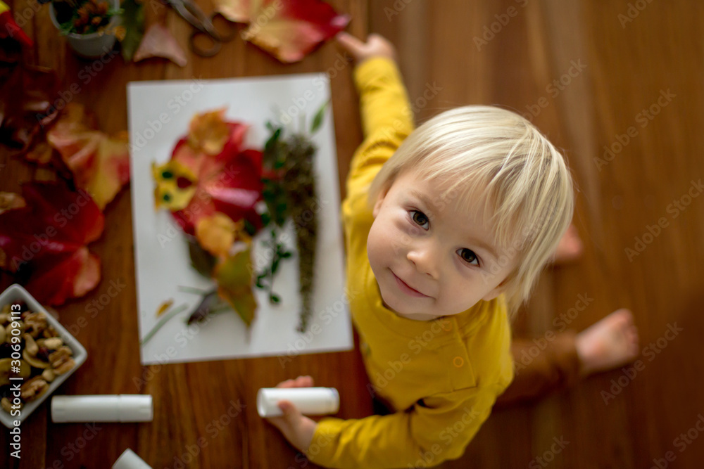Sweet child, toddler boy, applying leaves using glue Sweet child, toddler boy, applying leaves using glue