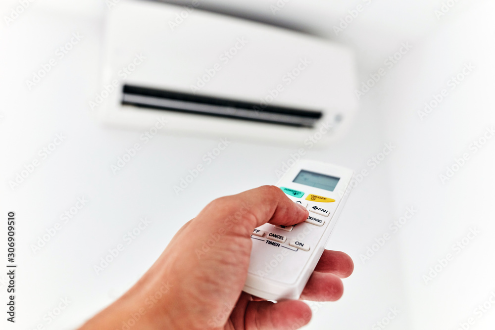 Modern air conditioner unit with a hand holding a remote. Modern air conditioner unit with a hand holding a remote.