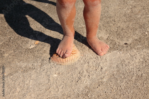 feet in the sand with shells and conchs in Florida beach