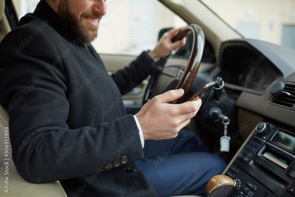 Young man sitting in the car and typing a text messaging on his mobile phone during driving Young man sitting in the car and typing a text messaging on his mobile phone during driving