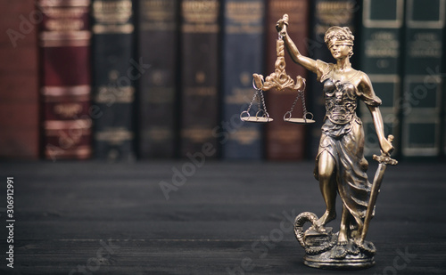 Scales of Justice, Justitia, Lady Justice and Law books in the background.