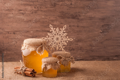 Honey and sticks of cinnamon  decorated with snowflake on bagging rustic background. Christmas holiday concept.