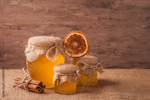 Honey and sticks of cinnamon decorated with dry orange on bagging rustic background. Christmas holiday concept.
