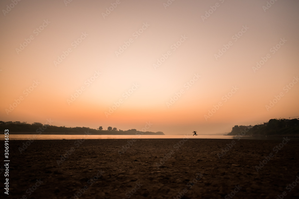 Silhouette man jumping at sunrise on the river Silhouette man jumping at sunrise on the river